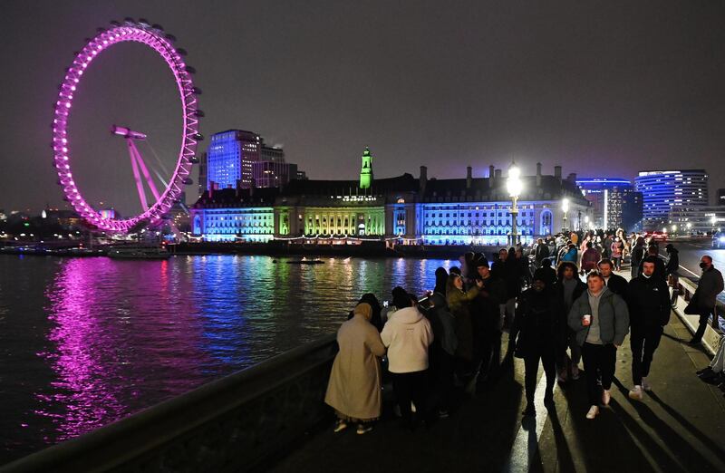 People gather on Westminster Bridge in front of the London Eye for New Years Eve in London. EPA