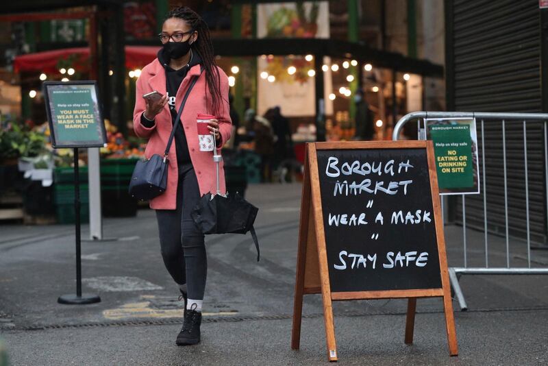 A shopper passes a coronavirus advice sign at Borough Market in London. AP Photo