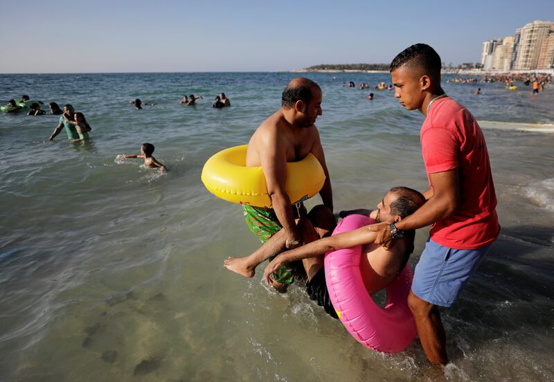 Workers at the beach in Alexandra help a disabled man into the water.