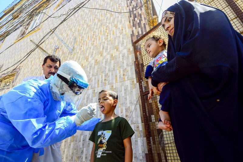 An Iraqi medic takes a oral swab from a boy in Iraq's central shrine city of Najaf on April 20, 2020, during the nationwide lockdown to stem the spread of the novel coronavirus.  / AFP
