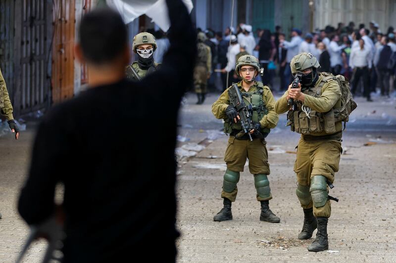 An Israeli soldier aims his rifle at a Palestinian during violence in Hebron. Reuters