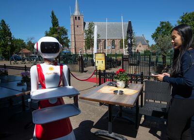 Leah Hu uses a tablet to demonstrate the use of a robot for serving purposes or for dirty dishes collection, as part of a tryout of measures to respect social distancing and help curb the spread of the COVID-19 coronavirus, at the family's Royal Palace restaurant in Renesse, south-western Netherlands, Wednesday, May 27, 2020. (AP Photo/Peter Dejong)