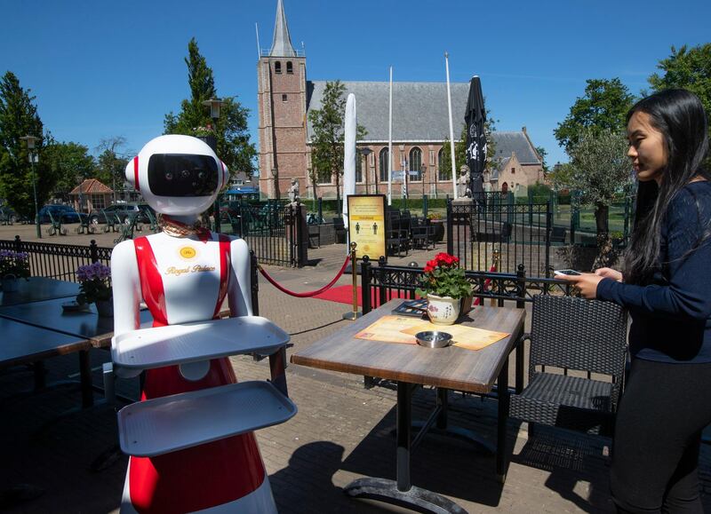 Leah Hu uses a tablet to demonstrate the use of a robot for serving purposes or for dirty dishes collection, as part of a tryout of measures to respect social distancing and help curb the spread of the COVID-19 coronavirus, at the family's Royal Palace restaurant in Renesse, south-western Netherlands, Wednesday, May 27, 2020. (AP Photo/Peter Dejong)