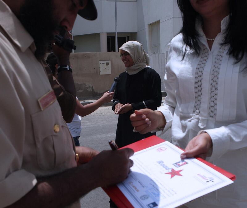 DUBAI-MAY 18,2008 - Police Lieutenant Obaid Humaid Obaid Al Zari ,(left), Dubai Police Traffic Department sign the certificate of safe driving to be awarded to Almas Rashid ,(middle) during presentation of awards in Al Garhoud, Dubai. ( Paulo Vecina/The National ) *** Local Caption ***  PV drive 9.JPGna19-roadsafety.JPG