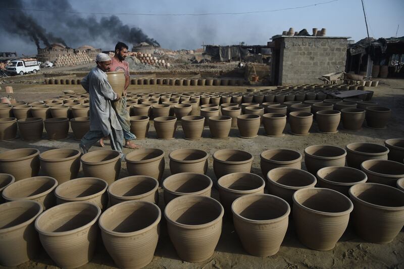 Potters set down a clay pot to dry at a workshop in Karachi, Pakistan. AFP