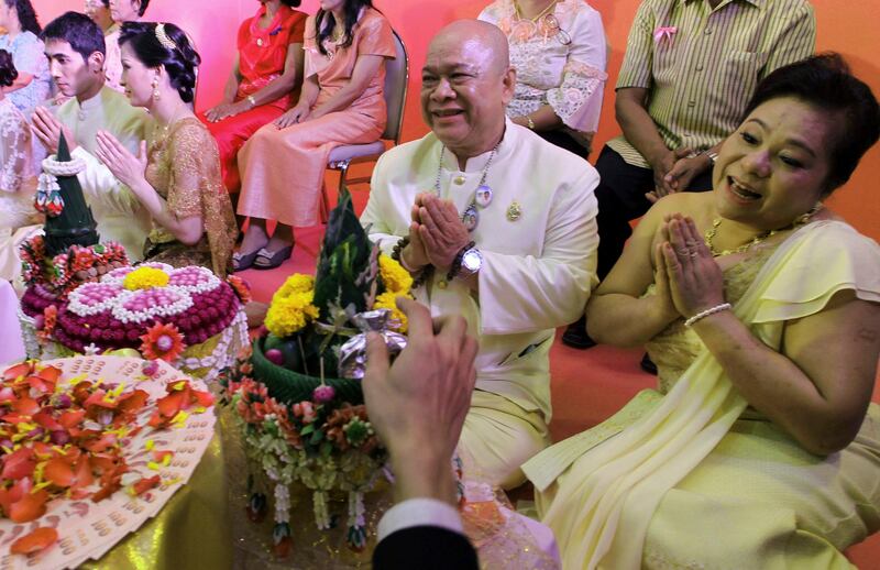 Reungsit Maksornteerachote, a 60-year old Thai groom, and his bride Ananya Ngarmarom, 50, right, get the blessing from a well-wisher during a mass wedding held to celebrate St. Valentine's Day in Bangkok, Thailand, Tuesday, Feb. 14, 2012. (AP Photo/Apichart Weerawong) *** Local Caption ***  Thailand Valentine Day.JPEG-02e92.jpg