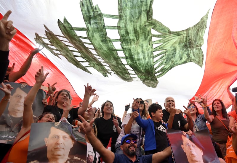 Supporters of the outgoing Lebanese President Michel Aoun pose under a national flag as they gather at Baabda Palace ahead of Aoun's farewell ceremony at the end of his term, Baabda, east of Beirut, Lebanon. EPA