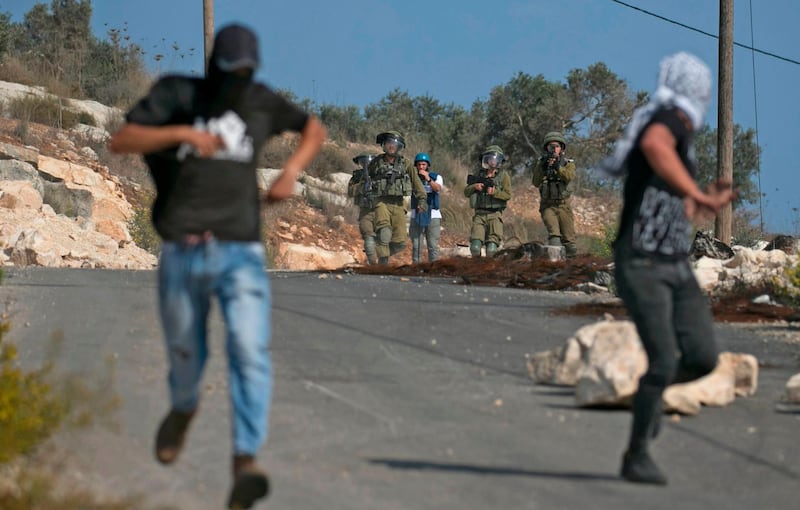 Palestinian protesters run from Israeli soldiers amid clashes following a weekly demonstration against the expropriation of Palestinian land by Israel in the village of Kfar Qaddum near the Jewish settlement of Qadumim (Kedumim), in the Israeli-occupied West Bank, on November 8, 2019.  / AFP / JAAFAR ASHTIYEH
