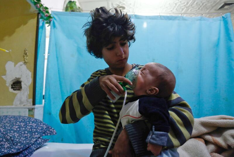 TOPSHOT - A Syrian boy holds an oxygen mask over the face of an infant at a make-shift hospital following a reported gas attack on the rebel-held besieged town of Douma in the eastern Ghouta region on the outskirts of the capital Damascus on January 22, 2018. 
At least 21 cases of suffocation, including children, were reported in Syria in a town in eastern Ghouta, a beleaguered rebel enclave east of Damascus, an NGO accusing the regime of carrying out a new chemical attack said. Since the beginning of the war in Syria in 2011, the government of Bashar al-Assad has been repeatedly accused by UN investigators of using chlorine gas or sarin gas in sometimes lethal chemical attacks.
 / AFP PHOTO / HASAN MOHAMED