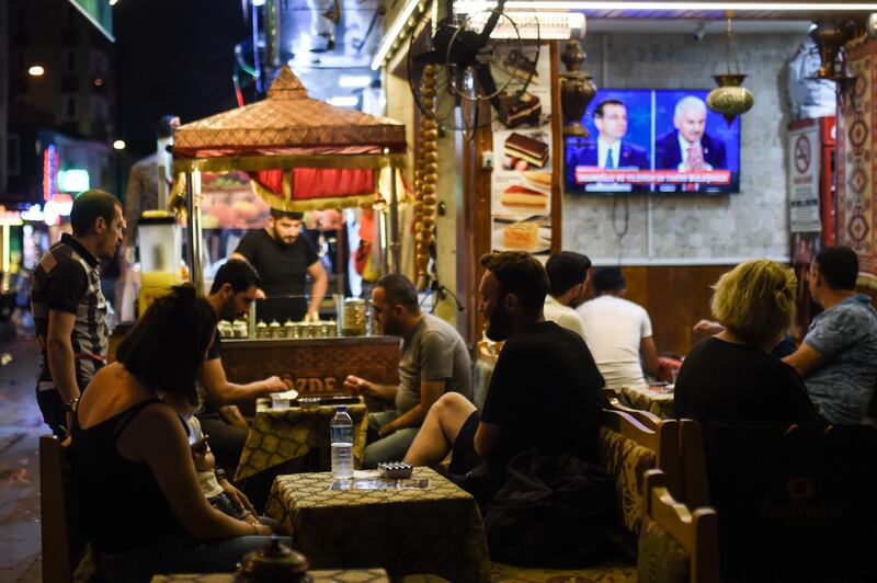 ISTANBUL, TURKEY - JUNE 16: People watch a television in a cafe as Istanbul mayoral candidate Binali Yildirim of the ruling Justice and Development Party (AKP) and Istanbul mayoral candidate Ekrem Imamoglu of the Republican Peoples Party (CHP) take part in a live television debate on June 16, 2019 in Istanbul, Turkey.  Anticipation has grown across Istanbul ahead of the live televised debate for the June 23 re-run Istanbul elections. Outdoor viewing areas have been set up across parts of Istanbul for the historic debate. The last major political debate in Turkey took place in 2002. Imamoglu won a narrow victory during the first mayoral election held in March, defeating the candidate from President Erdogan's Justice and Development Party (AKP) but Turkeys election body annulled the result after claims of voting irregularities, and a re-run election was announced for June 23. (Photo by Burak Kara/Getty Images)