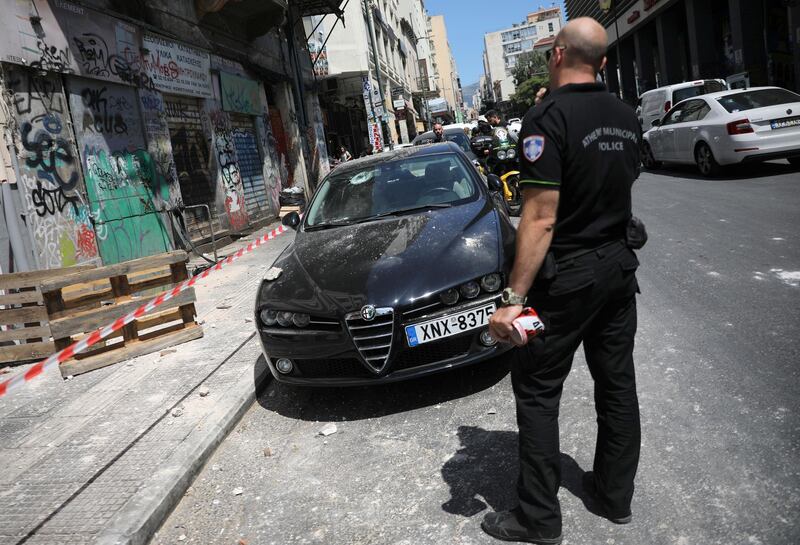 A police officer stands on a street next to a damaged car following an earthquake in Athens, Greece, July 19, 2019. REUTERS/Alkis Konstantinidis