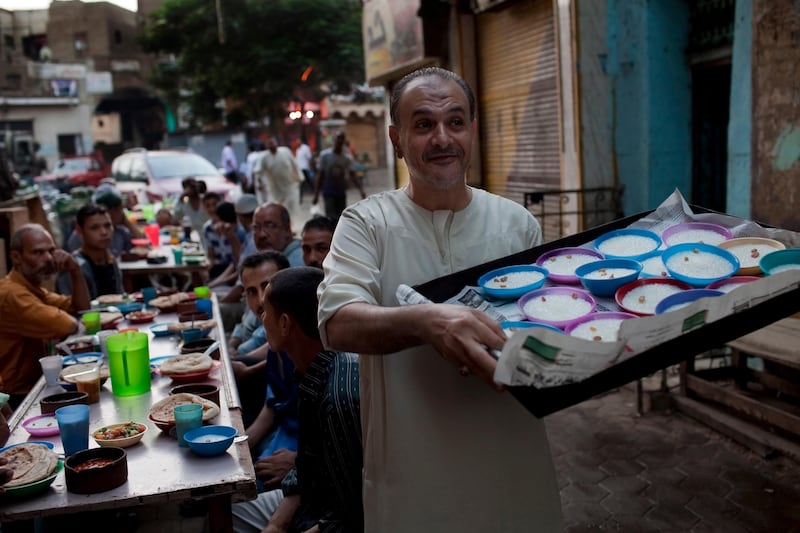 An Egyptian man distributes plates of rice pudding as part of a free iftar meal for the poor on a street in the Boulaq district of Cairo August 13, 2010. During Ramadan, wealthy individuals, charitable organizations and mosques traditionally distribute food to the poor. (Photo by Scott Nelson, for the National)