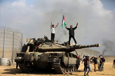 Palestinians on an Israeli Merkava tank at the Gaza Strip fence. AP