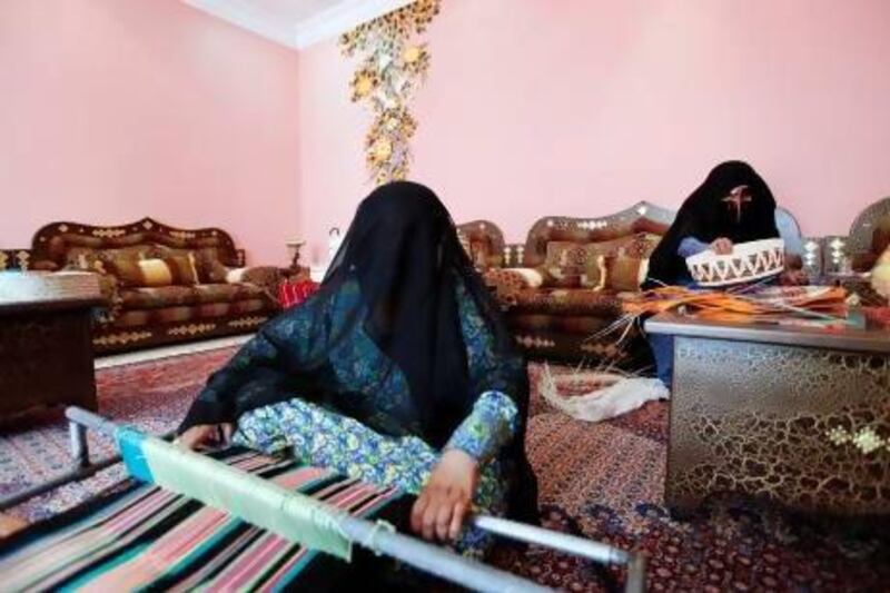 Hamda Al Mazrouei weaves a tablecloth while her mother Shamsa Al Mazrouei weaves a traditional basket in Madinat Zayed. Sarah Dea / The National