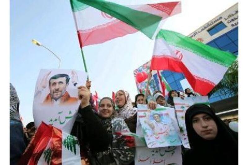 Lebanese Hezbollah supporters carry Iranian flags and posters of Iranian President Mahmoud Ahmadinejad upon his arrival at the main airport road in Beirut.