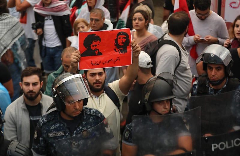 A protester holds a poster bearing the portraits of the founder of the Amal movement Imam Mussa al-Sadr, right, and Argentine-born revolutionary leader Ernesto 'Che' Guevara reading in Arabic "You are the cause leaders" at Riad al-Solh square in Beirut. AFP