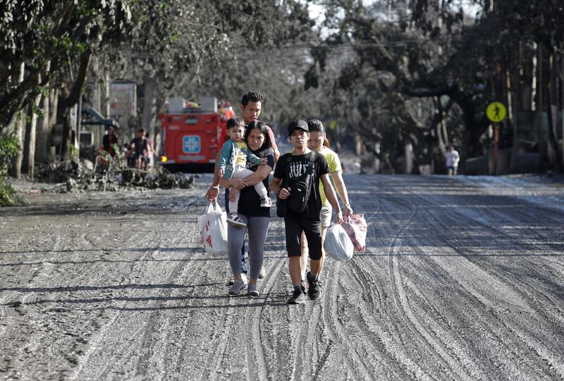A family walks along a road covered with ash from Taal volcano. AP Photo