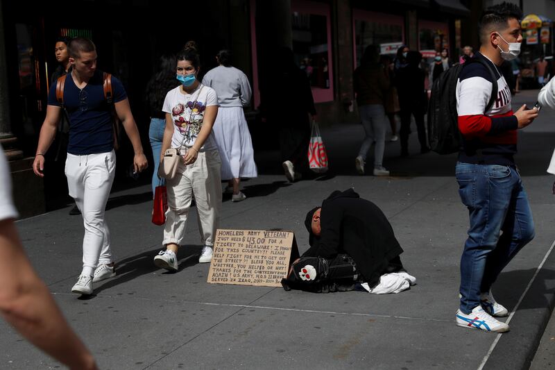 A homeless man with a sign asking for help, near Macy’s department store entrance in Midtown Manhattan. New York mayor Eric Adams described Saturday's shootings as 'senseless'. Reuters