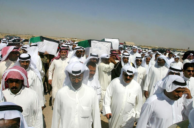 Relatives of Kuwaiti prisoners of war Nasser al-Onezi, Anam al-Aidan and Abdullatif al-Wahib, whose remains were found in a mass grave in southern Iraq, carry their coffins to the cemetery in Kuwait City 09 July 2003. The remains of four Kuwaitis who disappeared from the emirate during Baghdad's 1990-91 occupation, were found in a mass grave near Samawa, 200km south of Baghdad, bringing to seven the number of  Kuwaitis whose remains have been found in mass graves in Iraq since the fall of Saddam Hussein's regime three months ago following the invasion by US-led forces. Forensic teams from Kuwait are inspecting the mass graves and tracking down information on the 605 people who Kuwait says disappeared 12 years ago.      AFP PHOTO/Yasser AL-ZAYYAT (Photo by YASSER AL-ZAYYAT / AFP)