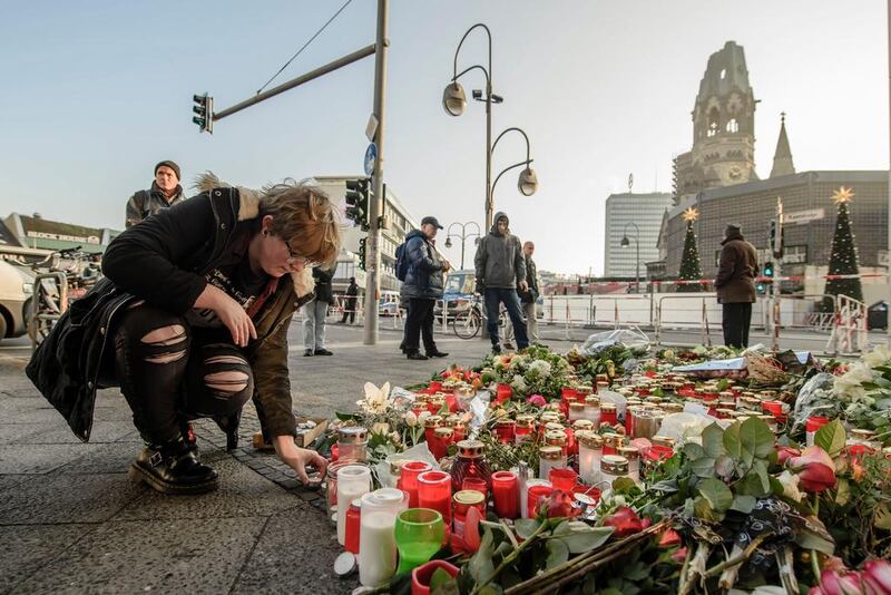 A mourner placing a candle on December 21, 2016 at a makeshift memorial near the Kaiser Wilhelm Memorial Church in Berlin, close to the site where a truck crashed into a Christmas market two days before. Twelve people were killed and almost 50 wounded, 18 seriously, when the lorry tore through the crowd on December 19, 2016. Clemens Bilan/AFP 