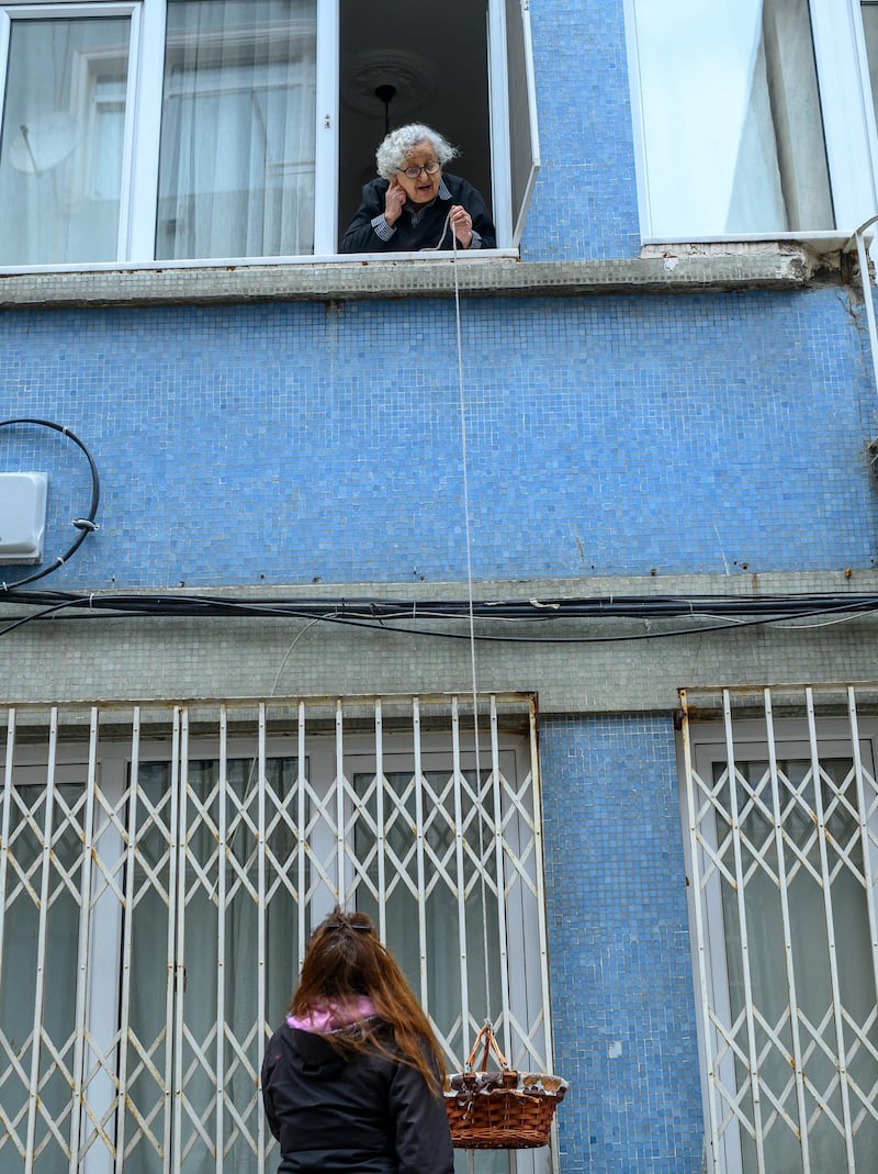 Lutfiye Yesilbas, an 89-year-old Turkish woman who lives alone in her home lowers her basket as her neighbour waits to take it at Kadikoy, in Istanbul.   AFP