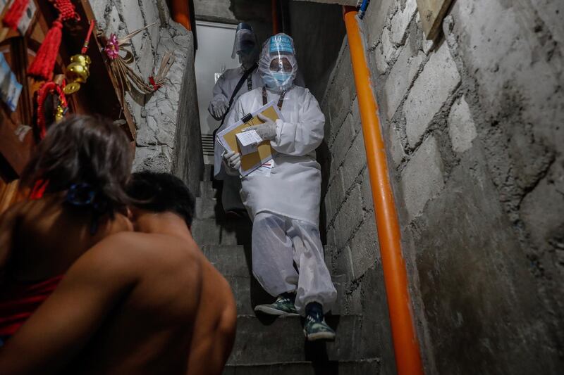 Health worker Richell Arsenio (R) goes down a stairway as a man carrying a girl goes inside their house in Manila, Philippines. Arsenio is part of a group of four volunteer health workers who were nicknamed 'Astronauts' by residents of Village 775, Zone 84 in Manila as they resemble such when donning their protective equipment. The healthcare volunteers conduct home visits twice a day to people infected or suspected to be infected with the novel SARS-CoV-2 coronavirus that causes the COVID-19 disease in one of the densely populated villages in Manila.  EPA