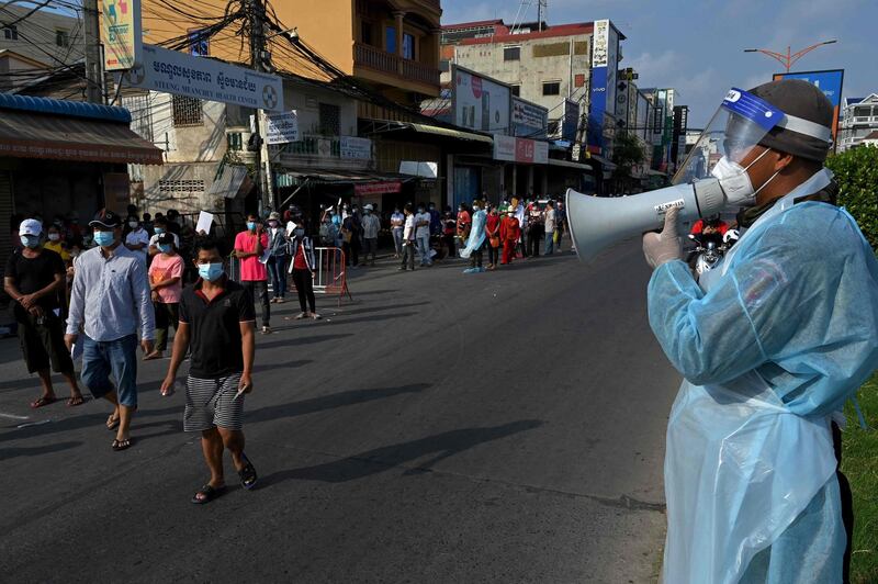 A soldier gives instructions as people line up to receive a dose of China's Sinopharm Covid-19 vaccine at a school in Phnom Penh, Cambodia. AFP