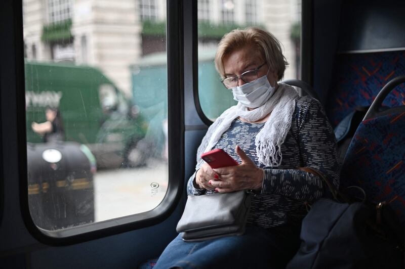 A passenger wears a protective face covering while travelling on a bus along Oxford Street in central London.