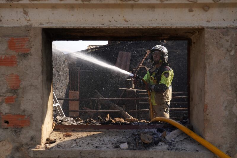 A firefighter douses rubble in a burnt house after a wildfire in Santibanez del Val near Burgos, Spain. AFP