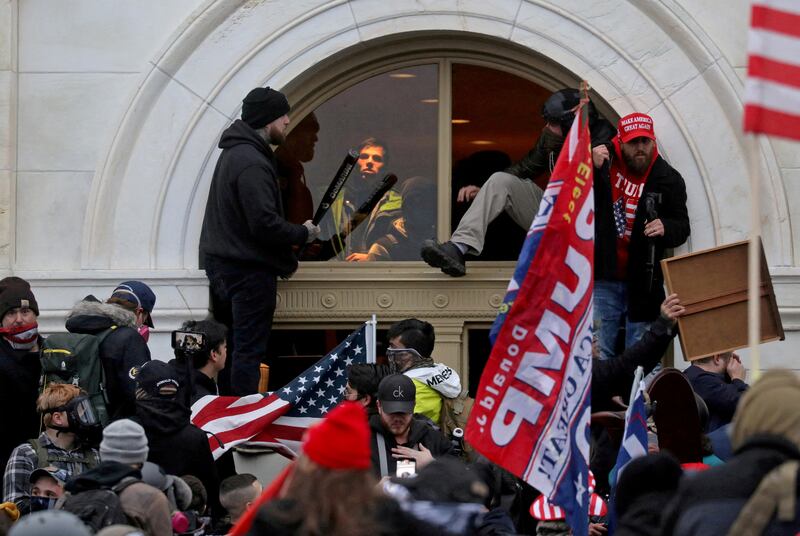 Supporters of then-US president Donald Trump climb through a window during the Capitol riot in Washington on January 6, 2021.  Reuters