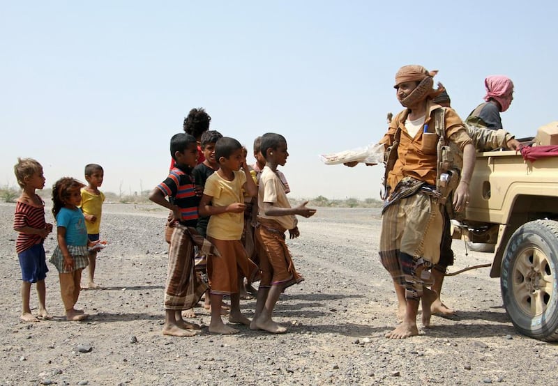 Pro-government fighters give food to Yemeni children on the road leading to the southwestern port city of Mokha on January 26, 2017. Saleh Al Obeidi / AFP Photo



