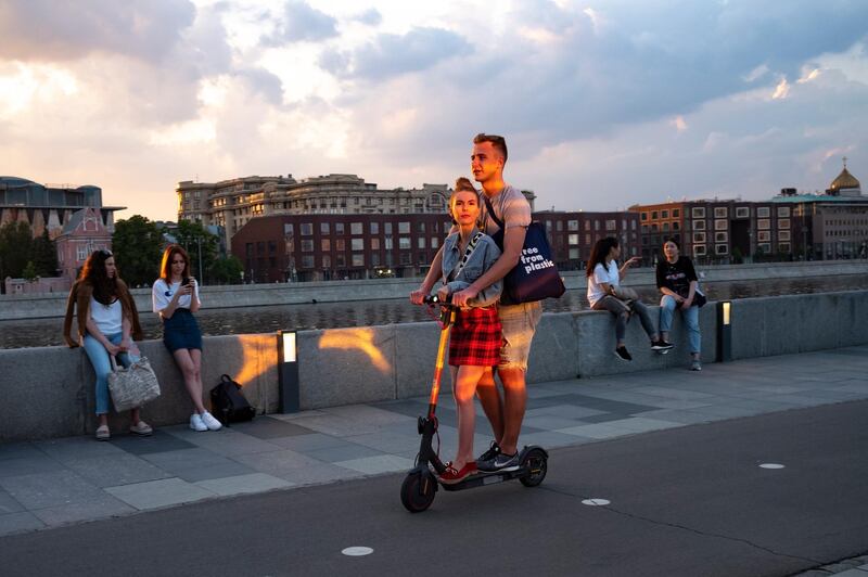 A couple ride a scooter along an embankment of the Moscow River during sunset in Russian capital. AP Photo