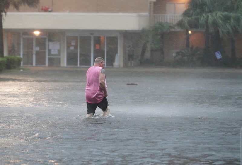 A man walks though a flooded parking lot as the outer bands of Hurricane Sally come ashore in Gulf Shores, Alabama. AFP
