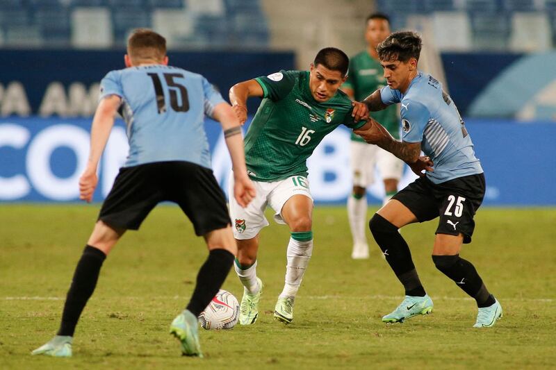 Bolivia's Erwin Saavedra (C) and Uruguay's Facundo Torres (R) battle for the ball. AFP