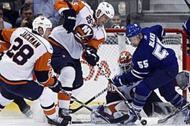 The Leafs forward Jason Blake, right, battles for the puck with Islanders' forward Tim Jackman, left, and defenseman Andy Sutton as the goalie Dwayne Roloson watches on.