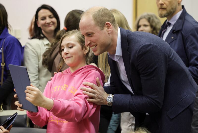 Prince William poses for photos with a young Ukrainian resident. Reuters