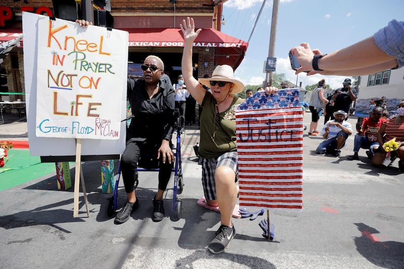 Robin Puttin leads a prayer while kneeling and raising her hand on the first anniversary of George Floyd's death, at George Floyd Square, in Minneapolis, Minnesota. Reuters