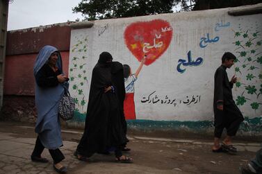 Afghan women pass by a wall with graffiti reading 'Peace' in Herat, Afghanistan. EPA