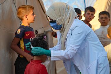 A Syrian doctor, on her own initiative, instructs children how to properly wear a mask during the Covid-19 outbreak, in a displacement camp in Idlib. AFP