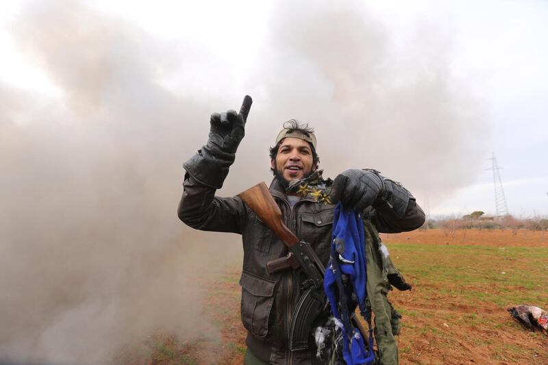 Rebel fighter holds parts of the uniform of the pilot from the Syrian government helicopter that was shot down in Idlib province. AP