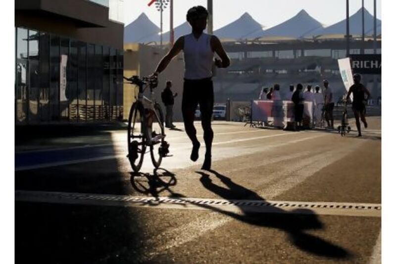 An athlete dismounts his bicycle and moves onto the running part during the Yas Triathlon in Abu Dhabi yesterday.