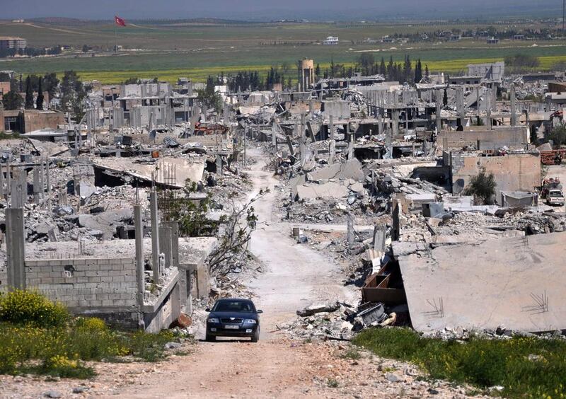 A car passes through an area of Kobani that was destroyed during the battle for the northern Syrian town between US-backed Kurdish forces and ISIL fighters. Mehmet Shakir / AP Photo