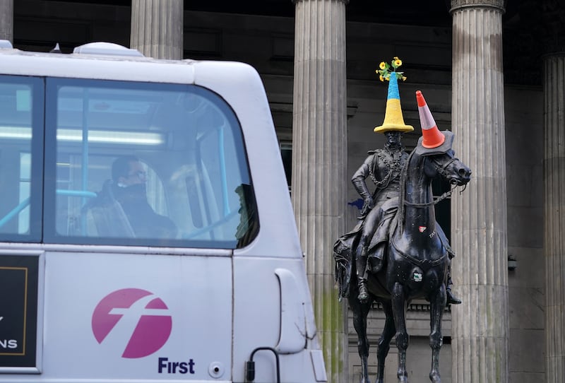 A bus passes the Duke of Wellington statue, which has a traffic cone in the colours of the flag of Ukraine placed on top of it, in Glasgow, Scotland. AP