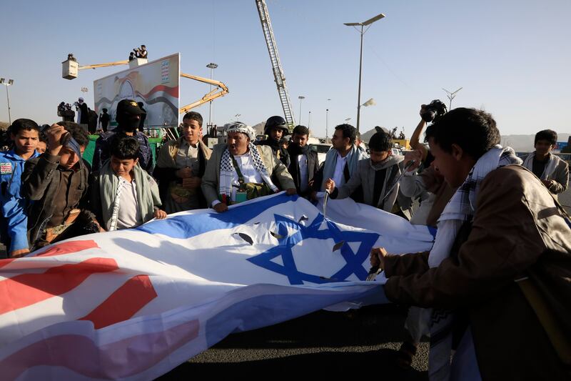 People prepare to burn the Israeli and US flags during the protest in Sanaa. EPA