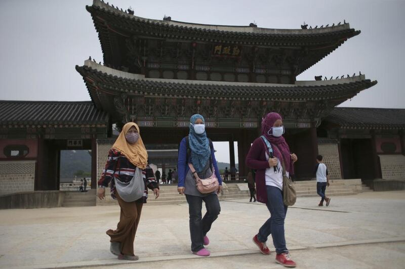 Tourists at Gyeongbok Palace, Seoul, South Korea, take precautions against the Mers virus. The government announced yesterday that it was strengthening measures to stem the spread of the disease, and public fear. Lee Jin-man / AP Photo
