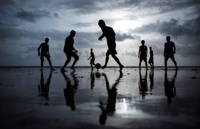 People are silhouetted as they play football at a beach along the Arabian Sea in Mumbai, India, on June 25, 2014.   Danish Siddiqui / Reuters