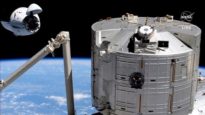 In this image made from NASA TV, the SpaceX Crew Dragon spacecraft, left, approaches to the International Space Station. The recycled SpaceX capsule carrying four astronauts has arrived at the International Space Station, a day after launching from Florida. NASA via AP