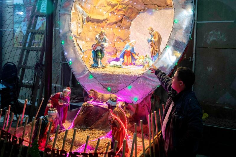 An Egyptian Christians worshipper stands by a nativity scene as he attends the Christmas Eve mass at the Coptic Catholic St. Mark Church in Minya city. AFP