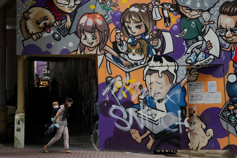 A woman and child wearing face masks on a street in Hong Kong, which reported 14,063 new coronavirus infections on Monday, the lowest in over three weeks. AP