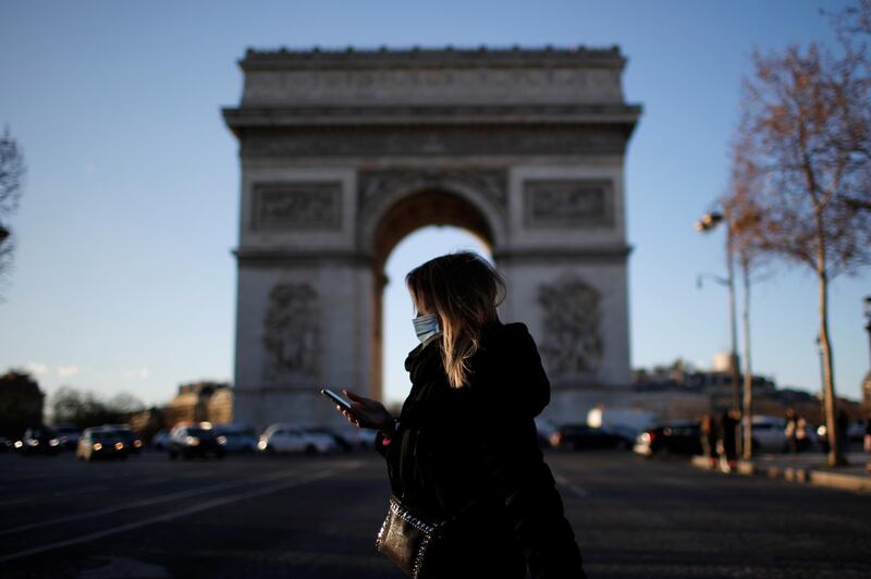 A woman, wearing a protective face mask, walks past Champs Elysees avenue near the Arc de Triomphe in Paris, France. Reuters